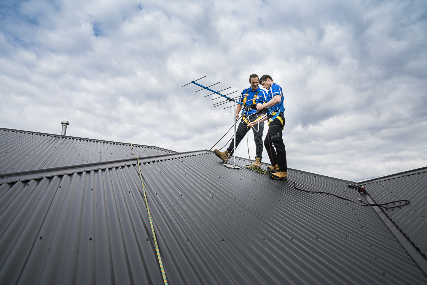 Professional technicians repairing a rooftop TV aerial in Australia, assessing whether repair or replacement is the best option for clear digital reception.