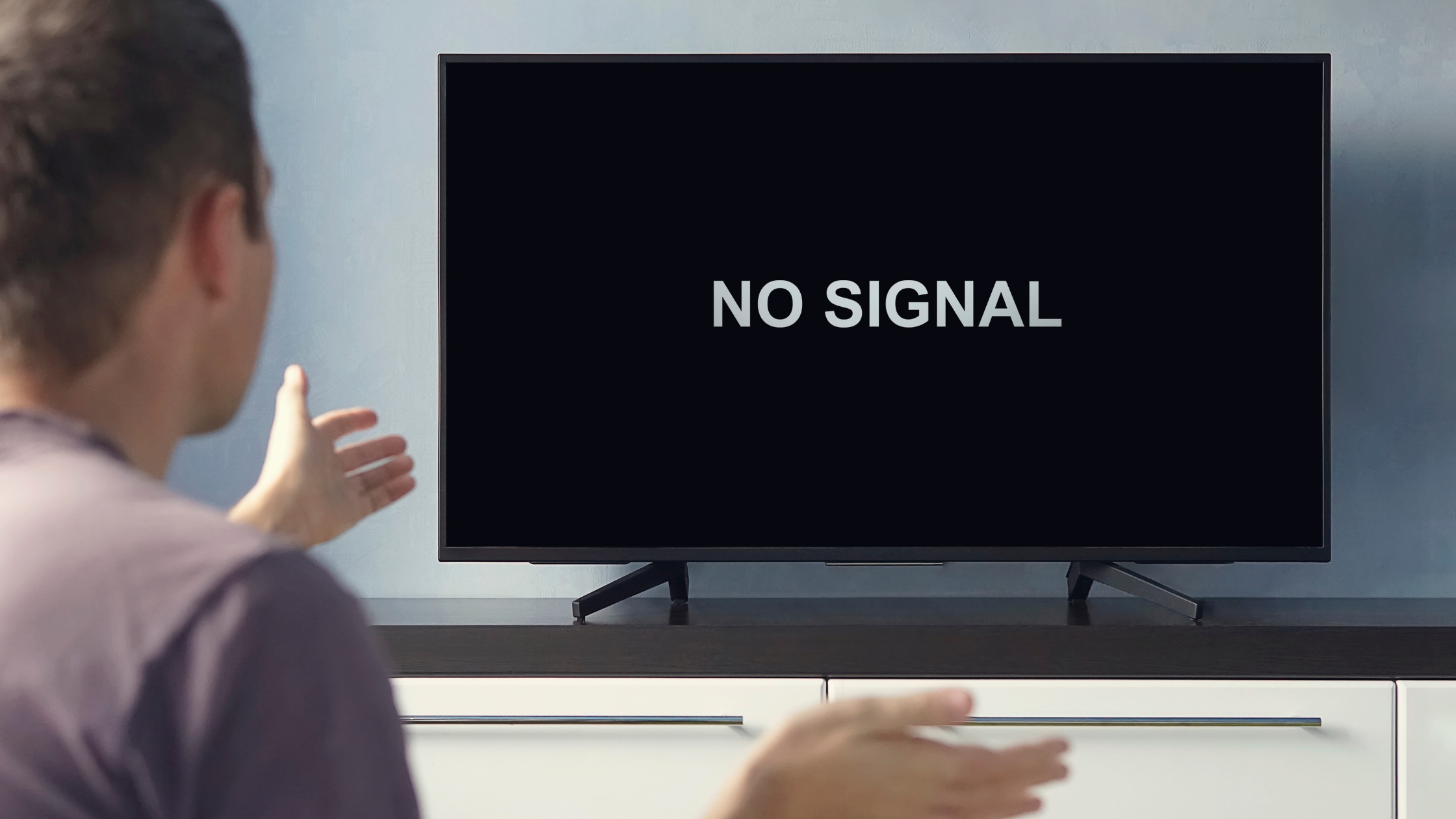 TV screen showing “No Signal” as a person gestures in frustration, representing storm-related TV reception problems and antenna signal drop.