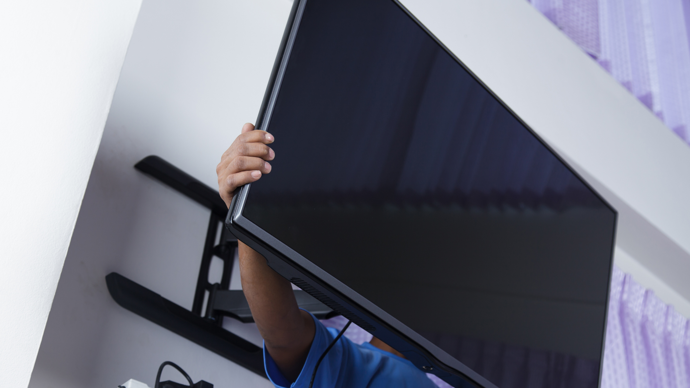 Homeowner attempting a DIY TV setup, highlighting the risks and extra costs that come with doing antenna installation yourself.