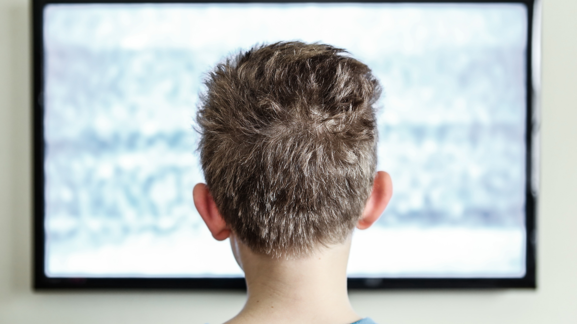 Television showing signal interference while a child watches TV indoors
