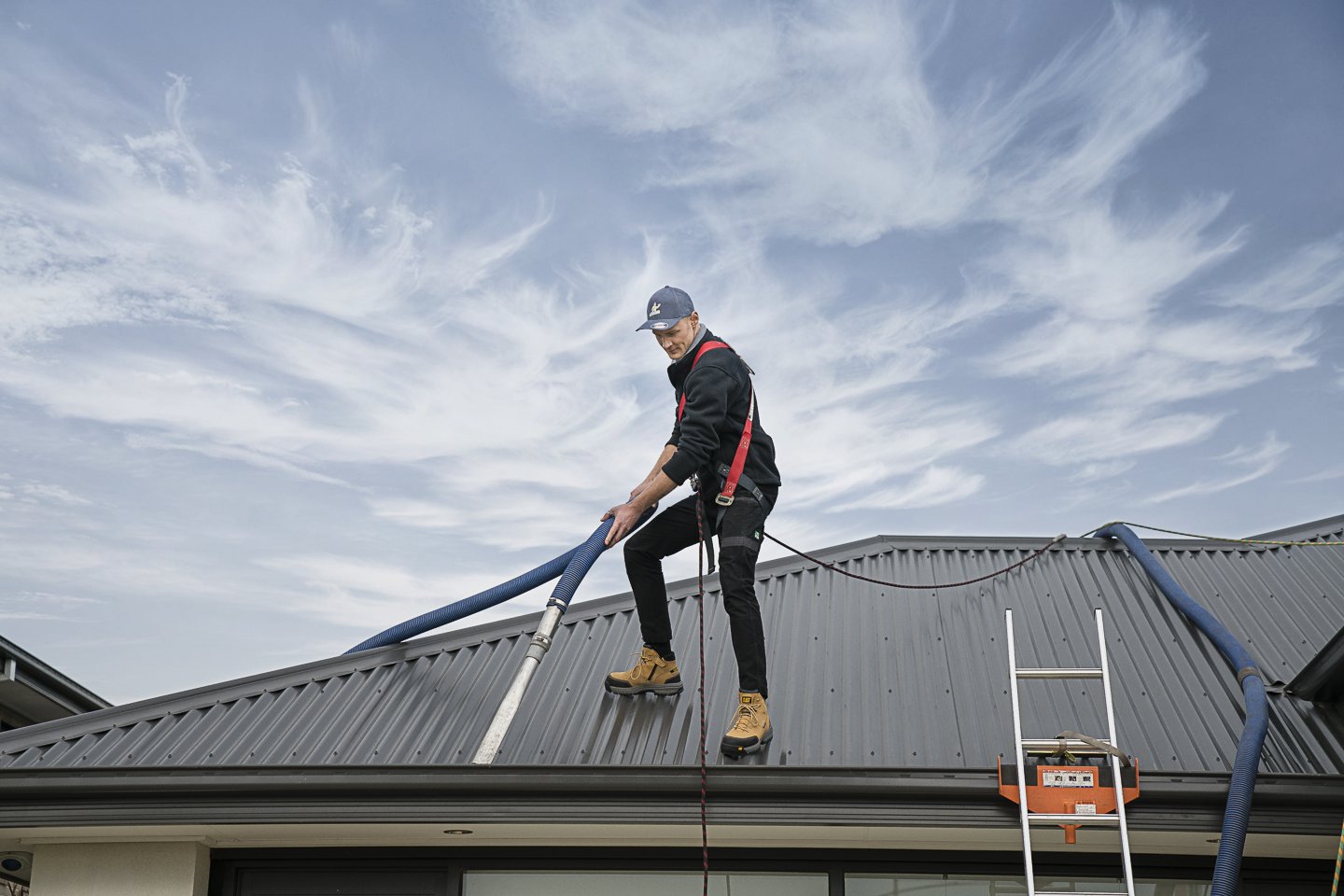 Professional gutter cleaner using vacuum equipment on a Melbourne home roof for safe and efficient gutter cleaning.