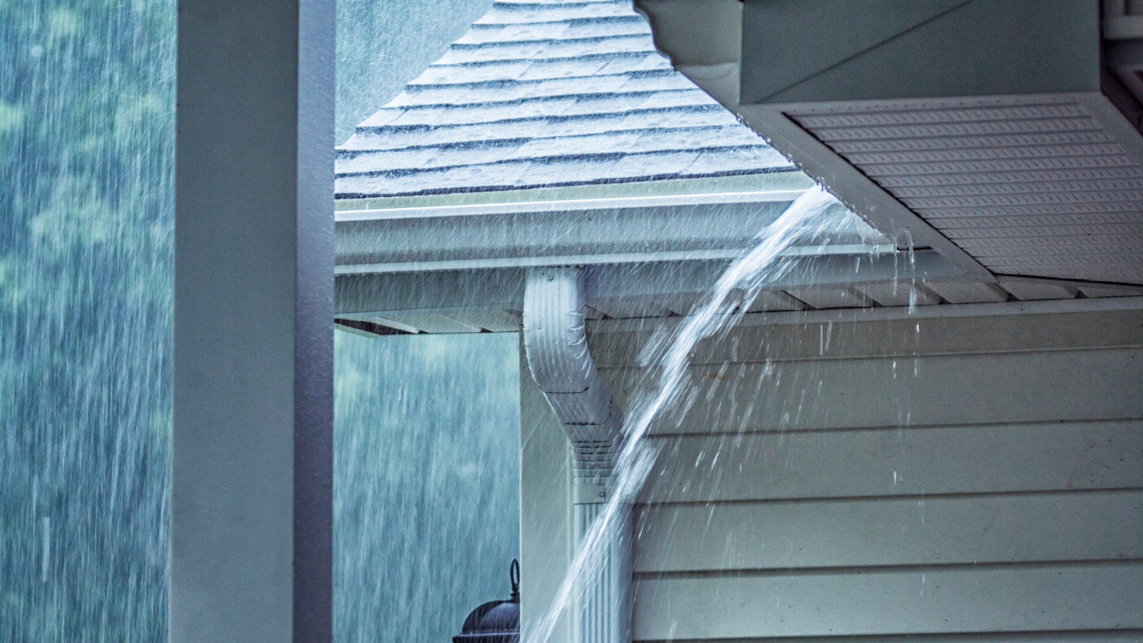 Overflowing gutter during heavy rain, showing how stormwater spills over and floods outdoor areas when gutters are blocked.