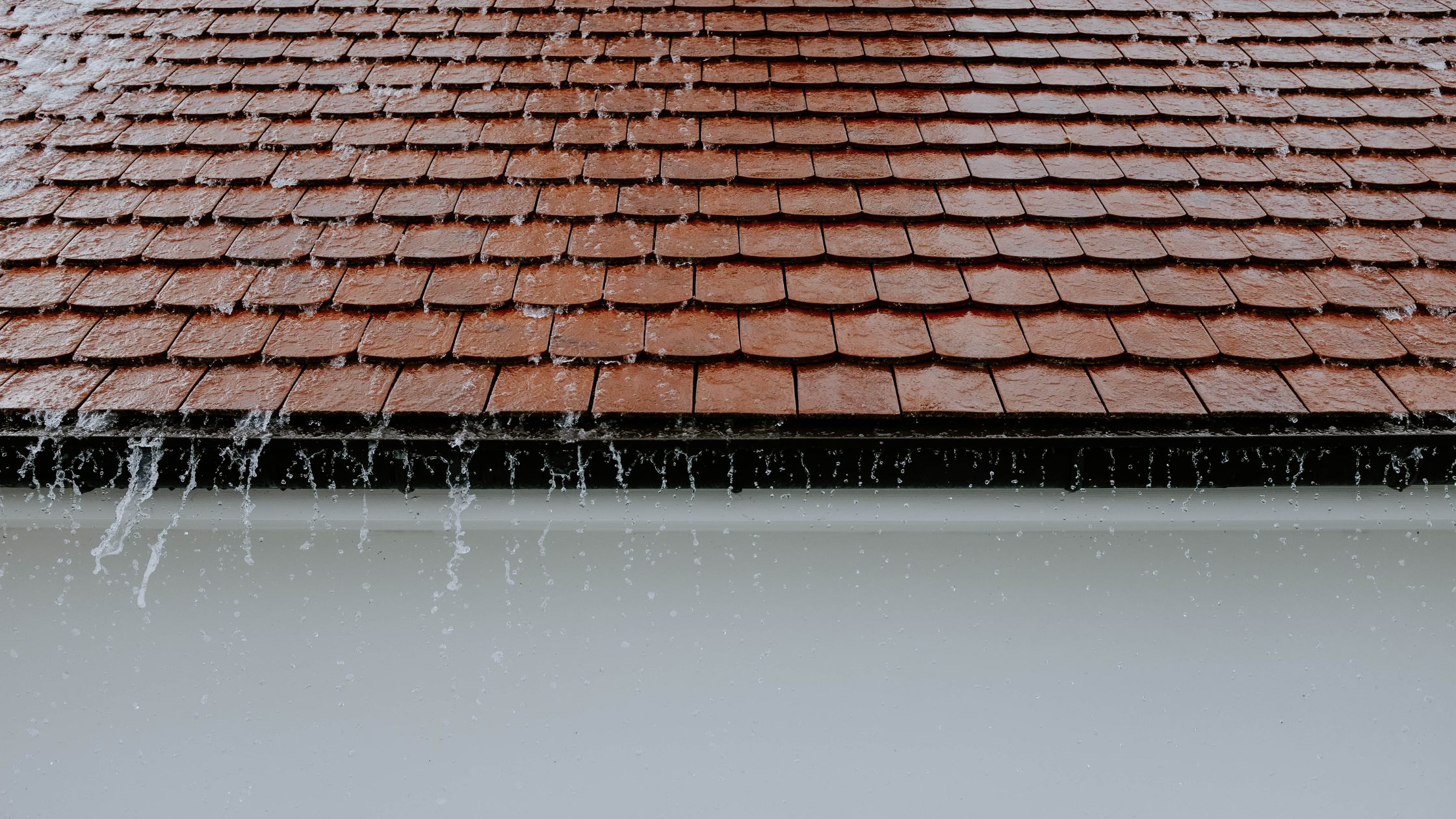 Rainwater overflowing from a roof due to undersized gutters, showing why Perth gutter cleaning is essential during heavy storms.