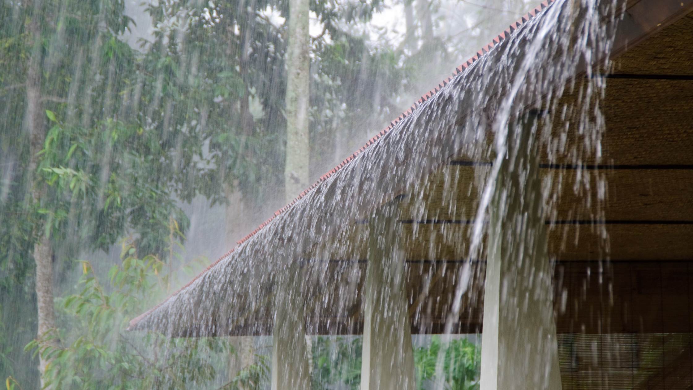 Heavy summer rain overflowing from a roof due to blocked gutters