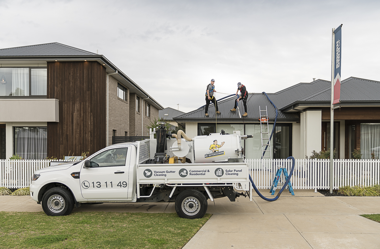 Mr Gutter Cleaning technicians using a professional vacuum gutter cleaning truck to safely clear gutters on a residential roof.