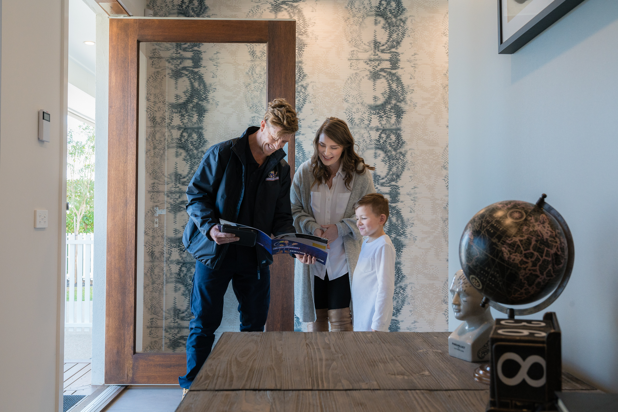 Pest control technician explaining a residential pest control plan to a family at their home, highlighting health and safety benefits.