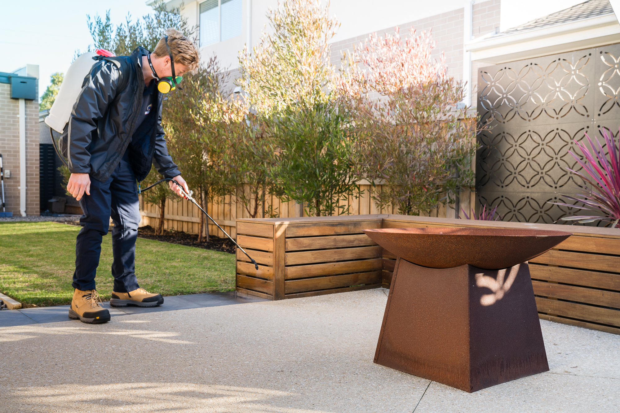 Professional pest control technician spraying an outdoor area during a termite inspection in Melbourne, showing how weather conditions impact termite pest control.