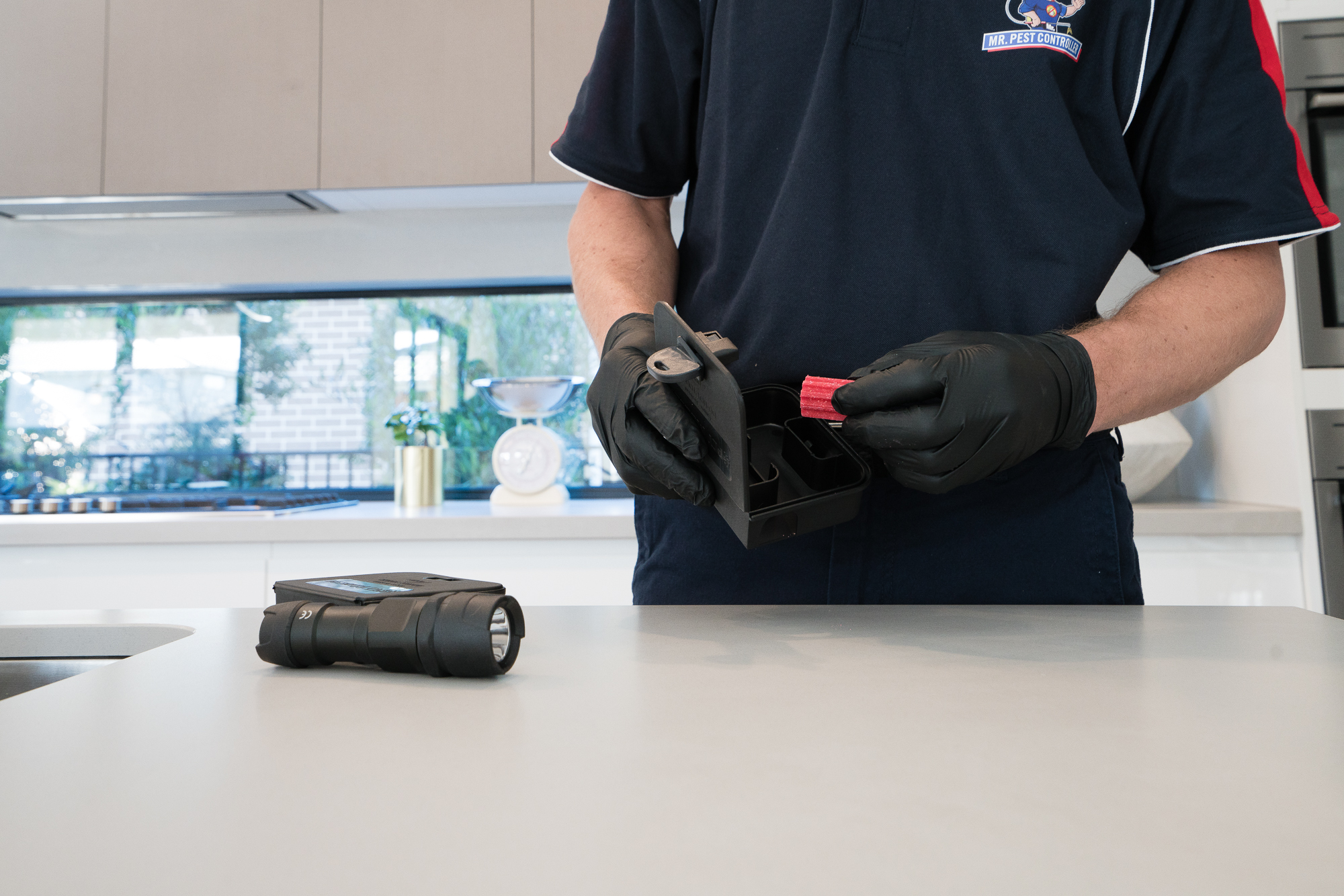Pest control technician preparing a bait station during a 24-hour pest control service in a Melbourne home.