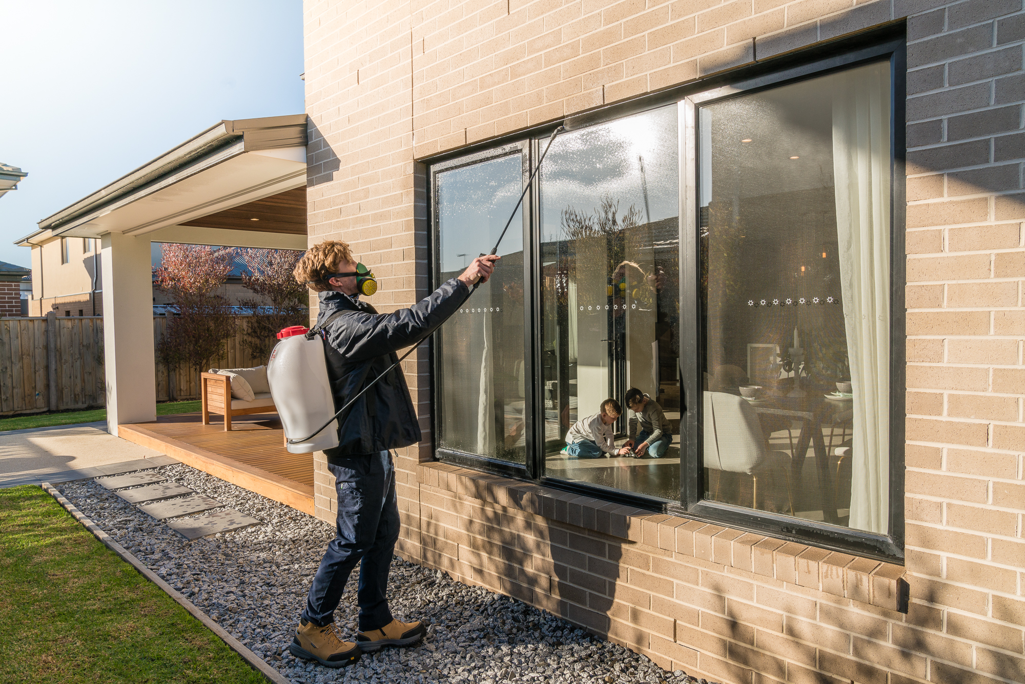 Professional pest control technician applying treatment to a residential home exterior as part of integrated cleaning and pest management